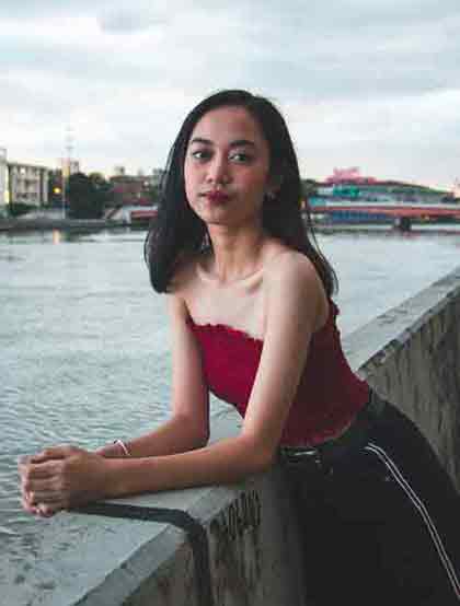 Young Filipino woman leaning on concrete